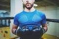 Young man boxing workout on ring in a fitness club. Caucasian male boxer in black gloves. Muscular strong man on