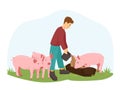 A young man or boy farmer feeds the pigs. The guy takes care of pigs, piglets. A farmer stands on a green lawn with pigs