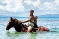 Young man with a boy riding horse on the beach on Taveuni Island