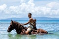 Young man with a boy riding horse on the beach on Taveuni Island