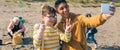 Young man and boy taking selfie to group of volunteers cleaning beach