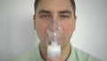 A young man breathes through an inhaler closeup. A man with an oxygen mask is being treated for a respiratory infection.