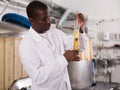 Young man brewer cin uniform hecking quality of beer in flask