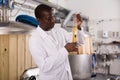 Young man brewer cin uniform hecking quality of beer in flask