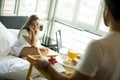 Young man brings breakfast in bed to young girl