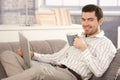 Young man browsing Internet at home smiling Royalty Free Stock Photo