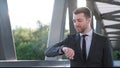 Young man in business suit looks at smart watch. Slow motion. Soft sunlight in the frame Royalty Free Stock Photo