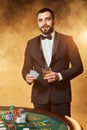 A young man in a business suit standing near poker table. Man gambles.