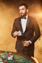 A young man in a business suit standing near poker table. Man gambles.