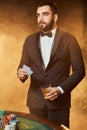 A young man in a business suit standing near poker table. Man gambles.