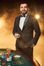 A young man in a business suit standing near poker table. Man gambles. Royalty Free Stock Photo