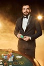 A young man in a business suit standing near poker table. Man gambles.