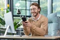 Young man businessman, freelancer sits in the office and uses the phone. Type messages, chstting Royalty Free Stock Photo