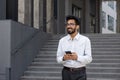 A young man, a businessman, a programmer walks through the city, holds the phone in his hands, smiles contentedly, types Royalty Free Stock Photo