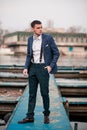 Young man businessman stands on pier against boat background