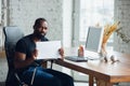 Young man, businessman working in office, looking on blank black computer screen, monitor, holding blank white sheet Royalty Free Stock Photo