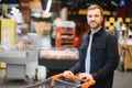 Young man buying groceries at the supermarket. Other customers in background. Consumerism concept. Royalty Free Stock Photo