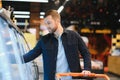 Young man buying groceries at the supermarket. Other customers in background. Consumerism concept. Royalty Free Stock Photo