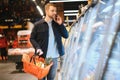 Young man buying groceries at the supermarket. Other customers in background. Consumerism concept. Royalty Free Stock Photo