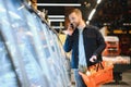 Young man buying groceries at the supermarket. Other customers in background. Consumerism concept. Royalty Free Stock Photo