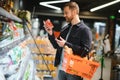 Young man buying groceries at the supermarket. Other customers in background. Consumerism concept. Royalty Free Stock Photo