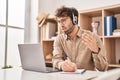 Young man call center agent writing on notebook speaking at office Royalty Free Stock Photo