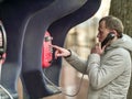 Serious young man calling by red street payphone