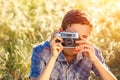 A young man with a camera taking pictures of the natural background sun rays tinted Royalty Free Stock Photo