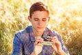 A young man with a camera taking pictures of the natural background sun rays tinted