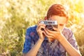 A young man with a camera taking pictures of the natural background sun rays tinted