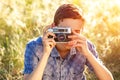 A young man with a camera taking pictures of the natural background sun rays tinted