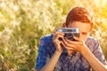 A young man with a camera taking pictures of the natural background sun rays tinted