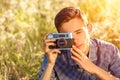 A young man with a camera taking pictures of the natural background sun rays tinted