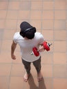 Young man with cap and headphones doing excercises weight training barefoot lifting arm with dumbbell on terrace outdoor Royalty Free Stock Photo