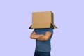 Man with a cardboard box on head folded his arms on his chest, isolated on lilac