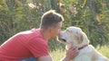 Young man caress, hugging and kissing his labrador outdoor at nature. Playing with golden retriever. Dog licking male