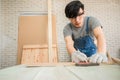 Young man carpenter wearing safety goggle using pencil and Iron ruler draw line on plank wood for furniture manufacturing in