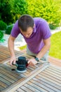 Young man - carpenter working with electric sander in the garden Royalty Free Stock Photo