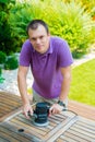 Young man - carpenter working with electric sander in the garden Royalty Free Stock Photo