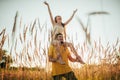 Young man carries girl on his shoulders at meadow. Royalty Free Stock Photo