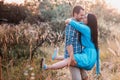 Young man carries in his arms a young attractive girl in a park