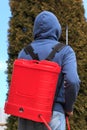 A man working in a garden showering shrubs with a special device