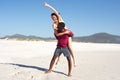 Young man carrying girlfriend on his back on beach