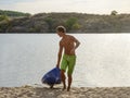 Young Man Carrying out Kayak to the Sand Beach from the Water on Beautiful River or Lake at the Evening Royalty Free Stock Photo