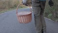 Young man carrying a wicker basket with gloves to recollect chestnuts