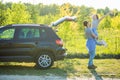 Young pretty man carrying a woman on his back near car while on a road trip Royalty Free Stock Photo
