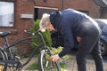 Young man in casual clothes cleaning rust and oiling his city cruiser bicycle chain and gear with spray before riding