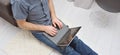 Young man in casual clothes sitting on floor and working on his laptop computer at home. Stay home and work online. Quarantine Royalty Free Stock Photo