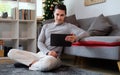 Young man in casual clothes sitting in living room and using digital tablet Royalty Free Stock Photo