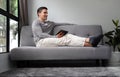 Young man in casual clothes sitting on sofa and using digital tablet Royalty Free Stock Photo